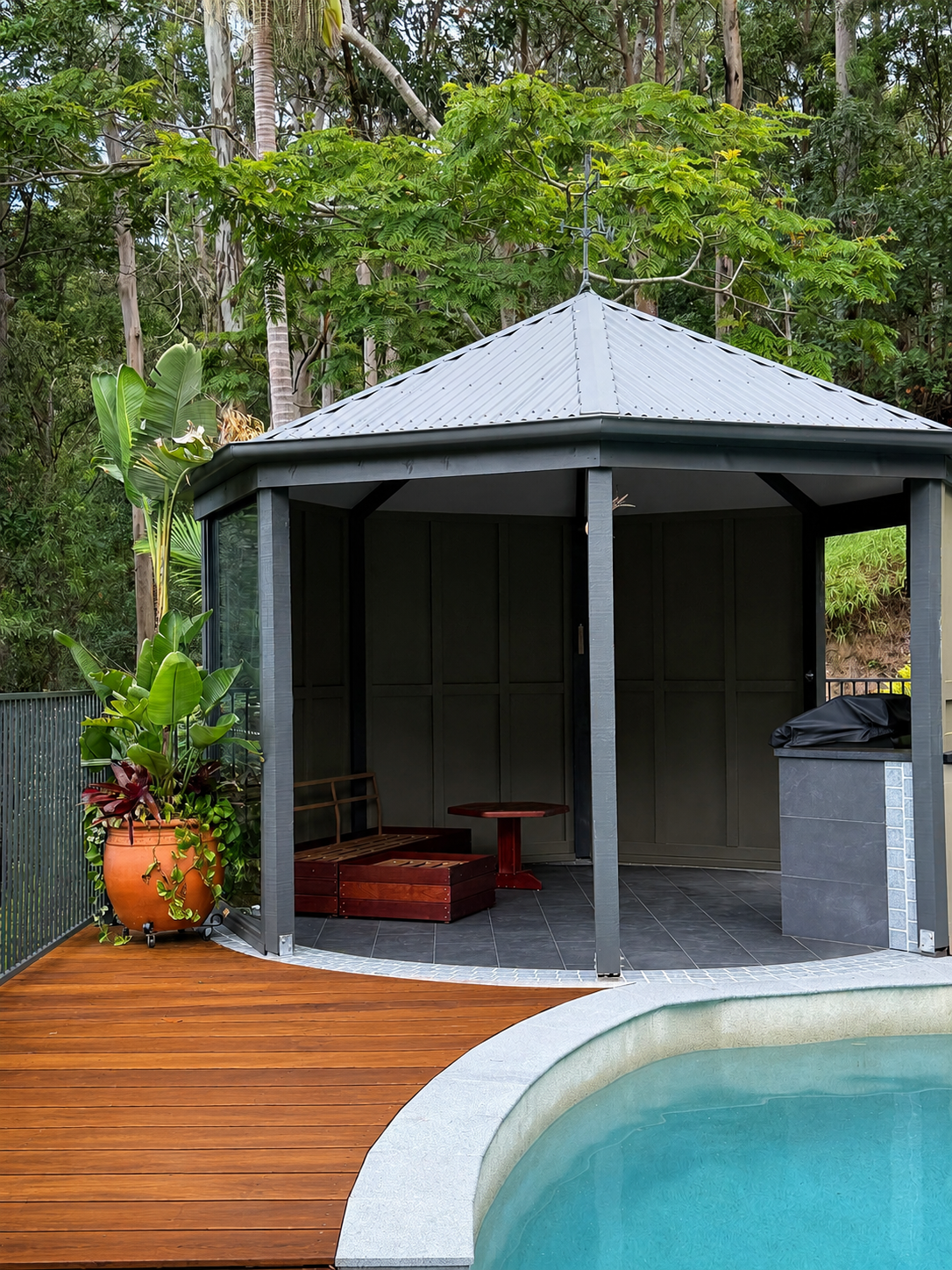Outdoor renovation with covered entertaining area, timber decking, pool and surrounding bushland.