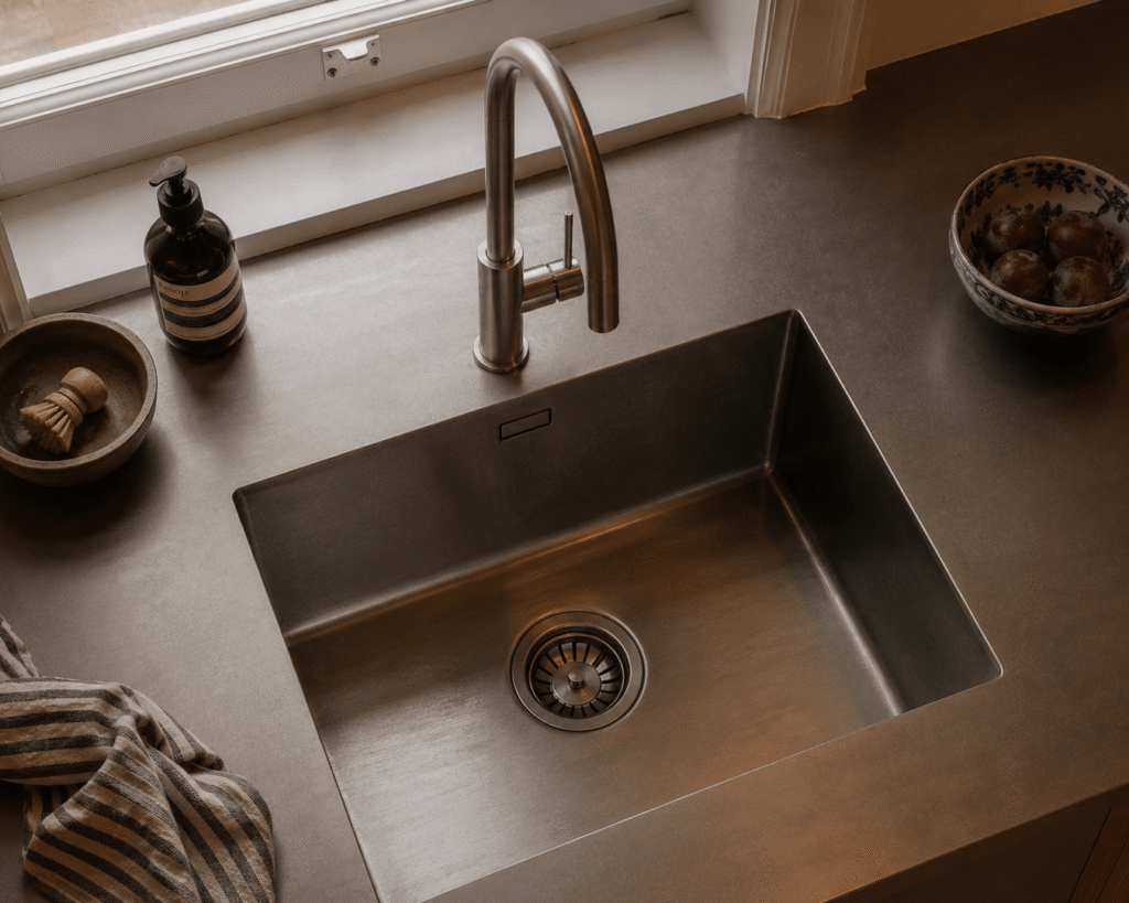 Close-up of a kitchen renovation gold coast. Deep stainless steel kitchen sink with stone benchtops, brushed nickel tapware and premium custom joinery.